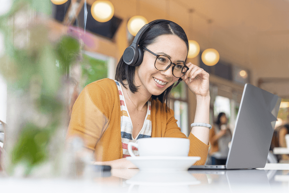 Eine Frau arbeitet mit dem Cisco 730 Headset und ihrem Laptop in einem Caf&eacute;